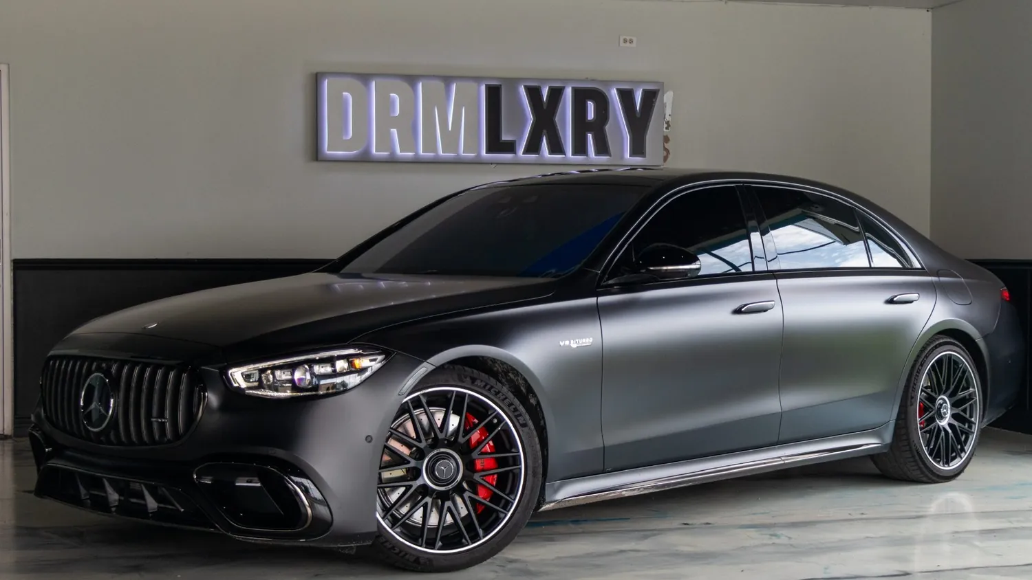 Matte black Mercedes-AMG S63 E Performance rental in Detroit, front three-quarter view facing left, in the DRMLXRY showroom