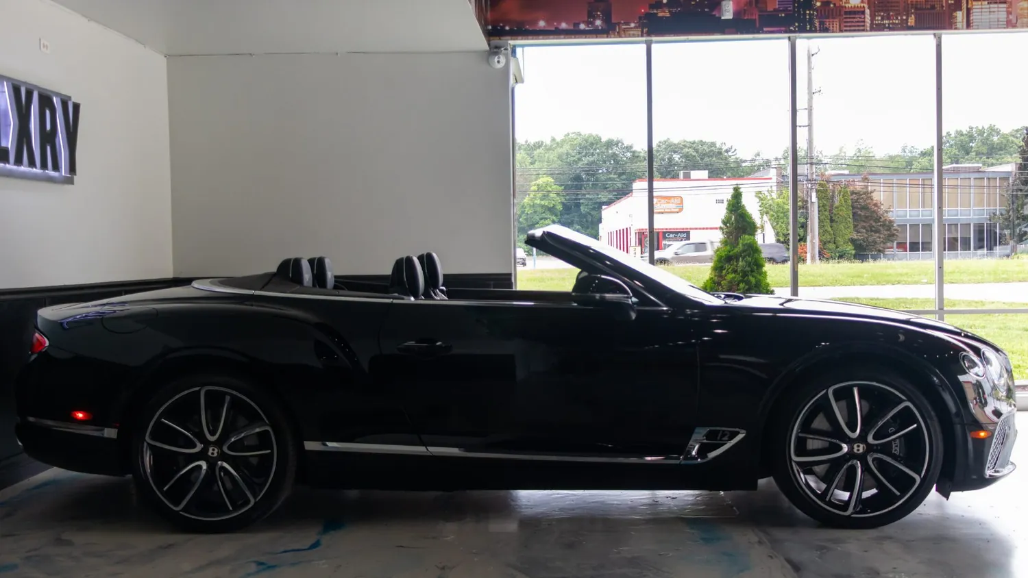 Black Bentley Continental GTC rental in Detroit, side profile with the roof down