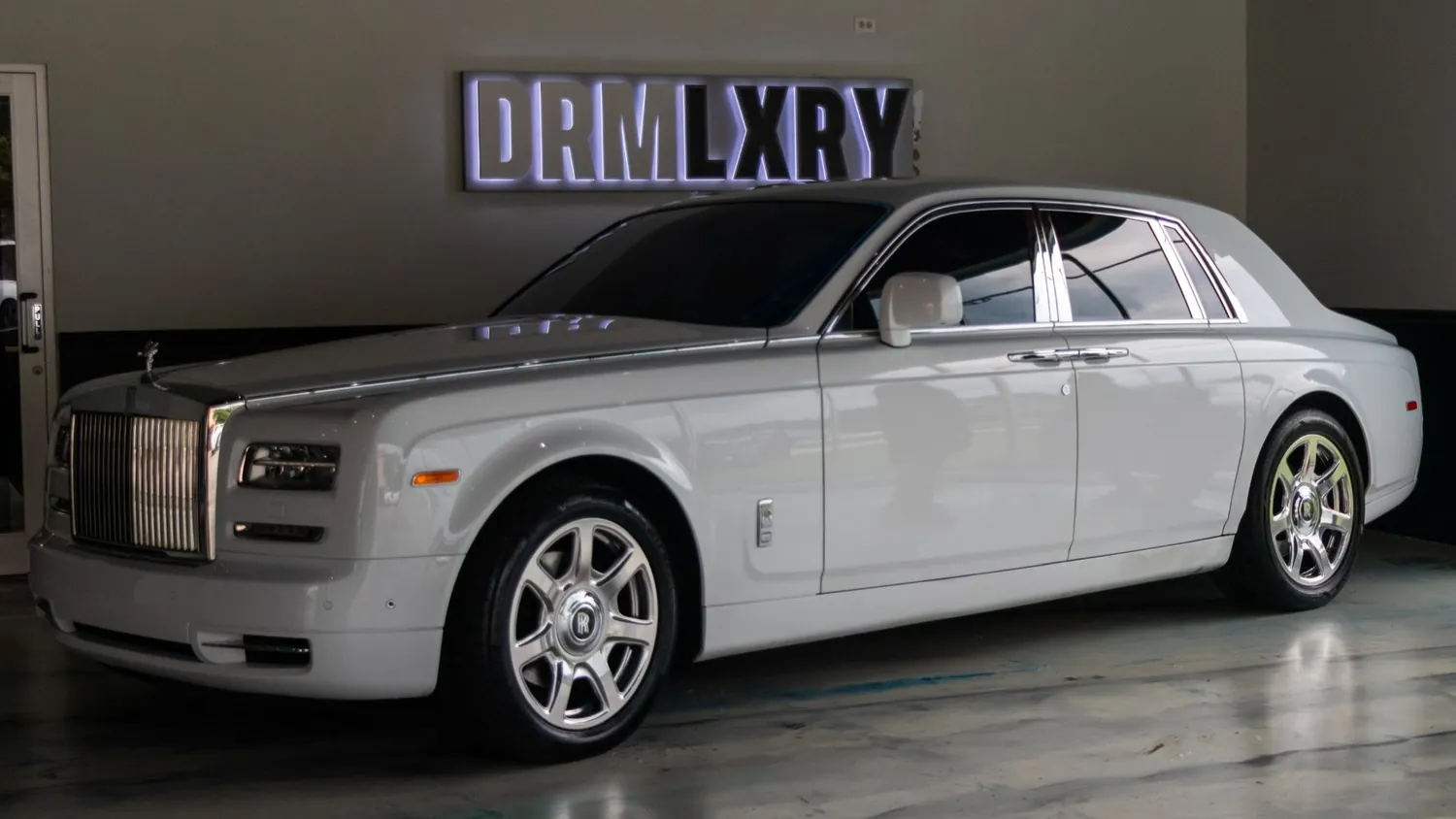 White 2017 Rolls-Royce Phantom rental in Detroit, front three-quarter view facing left, in the DRMLXRY showroom
