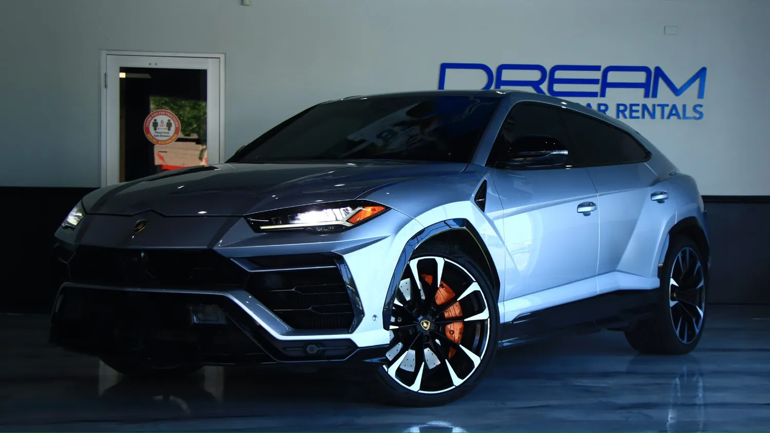Gray 2022 Lamborghini Urus rental in Detroit, front three-quarter view facing left, in the DRMLXRY showroom