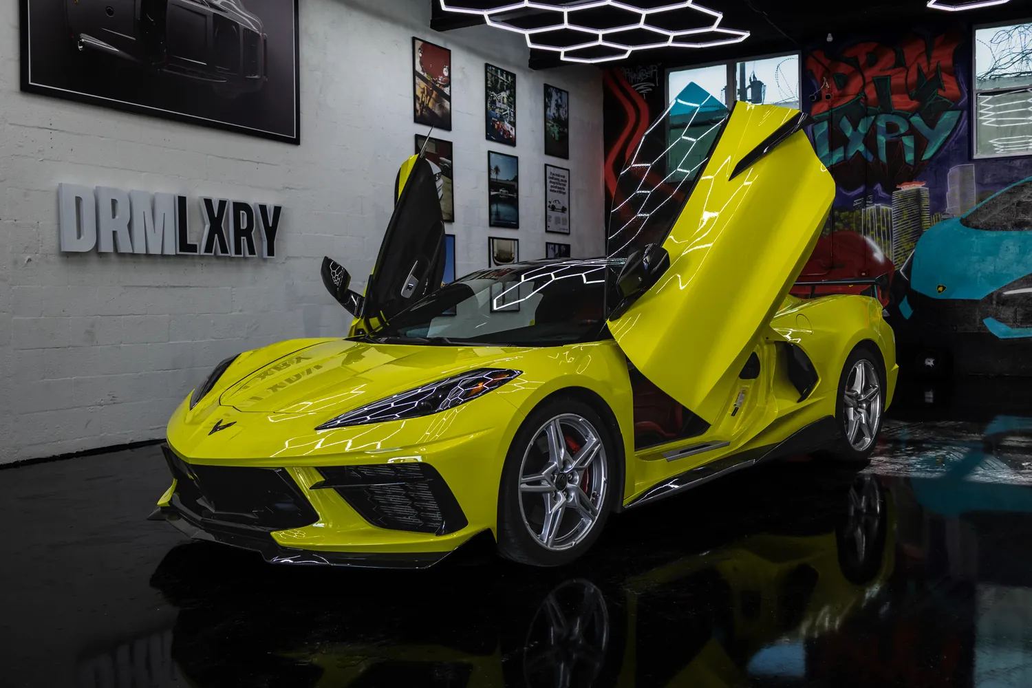 Yellow 2021 Chevrolet Corvette Stingray, front three-quarter view facing left with its vertical doors open, in the DRMLXRY Miami showroom