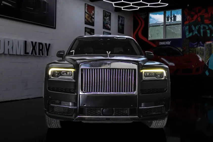 Front view of the black Rolls-Royce Cullinan with illuminated headlights